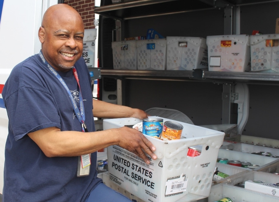 NALC Letter Carrier unloading bins of donated food from a mail truck