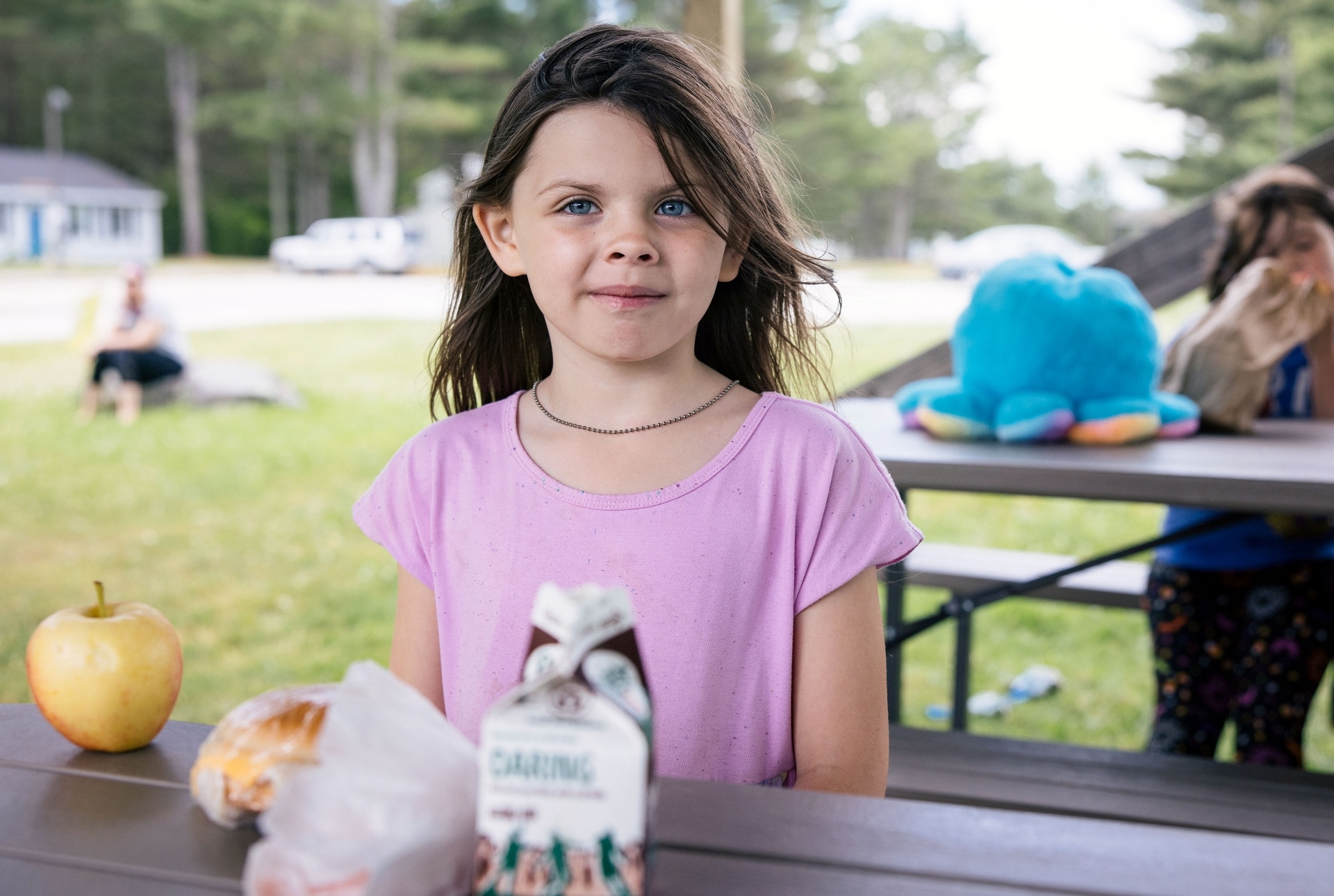 A child enjoys lunch in the park with her friends as part of a summer meals program.